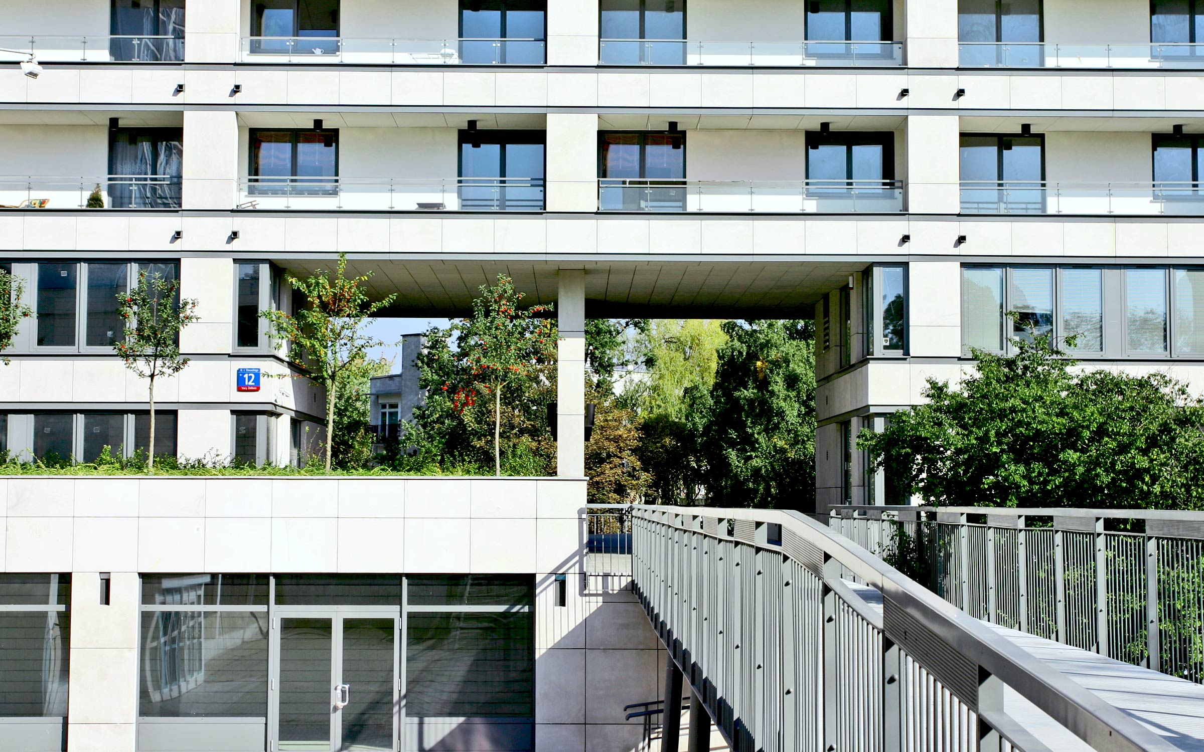 A bridge leads the way into the green courtyard of a residential complex